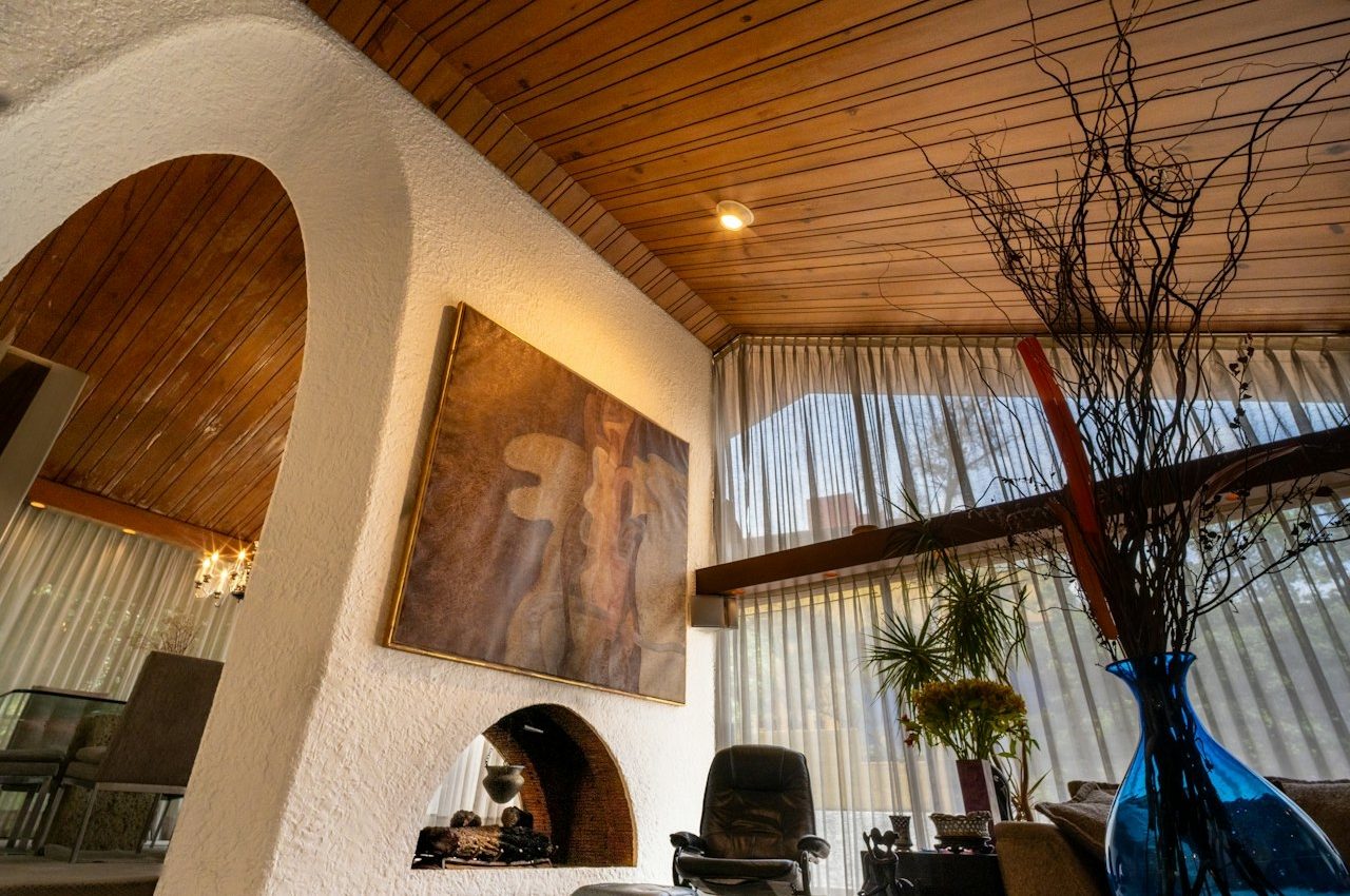 Salon d'inspiration méditerranéenne avec plafond voûté en bois, mur en arche et grand tableau abstrait