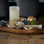 Bougie allumée, pommes de pin et rondins de bouleau dans un plateau en bois, idée de déco de Noël récup nature